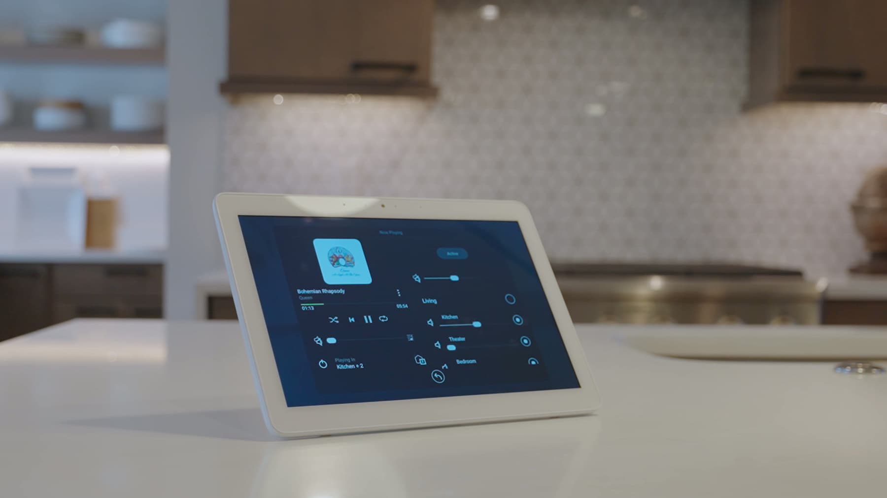 A control tablet on a kitchen counter showing audio and lighting for the whole house